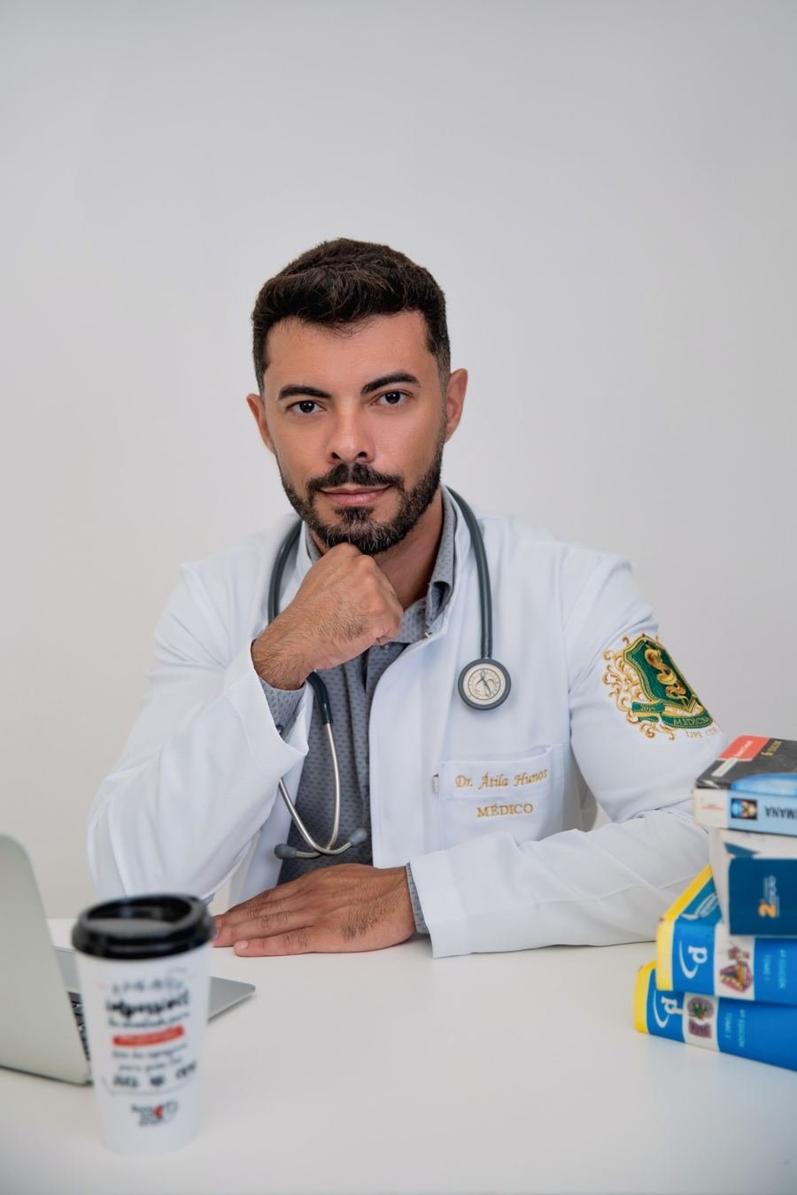 Dr. Átila Hunos sentado à mesa de atendimento